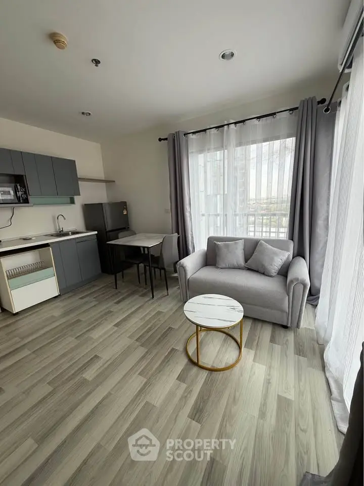 Modern living room with open kitchen, featuring sleek gray cabinets and cozy seating area.