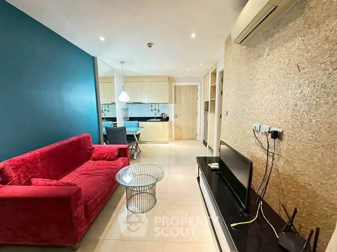 Modern living room with vibrant red sofa and open kitchen layout, ideal for cozy urban living.