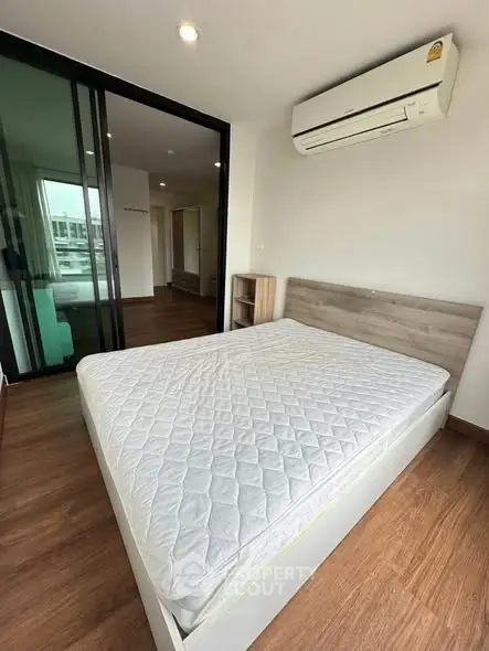 Modern bedroom with wooden flooring and air conditioning in a stylish apartment.