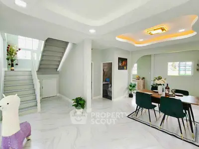 Modern open-plan living area with stylish dining space and staircase, featuring elegant decor and ample natural light.