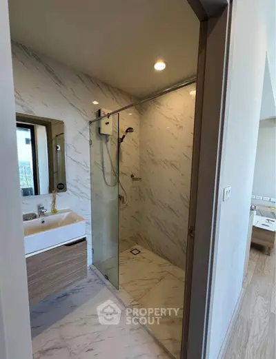 Modern bathroom with glass shower and marble tiles in luxury apartment.