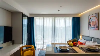 Modern studio apartment with stylish decor and large windows offering natural light.