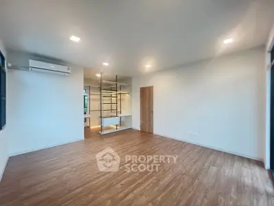 Spacious modern living room with wooden flooring and built-in shelving