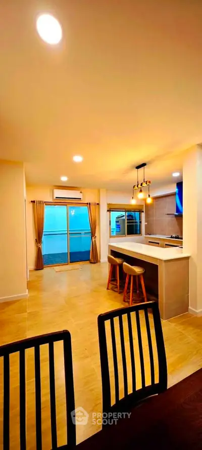 Spacious open-plan kitchen and dining area with modern lighting and large windows.