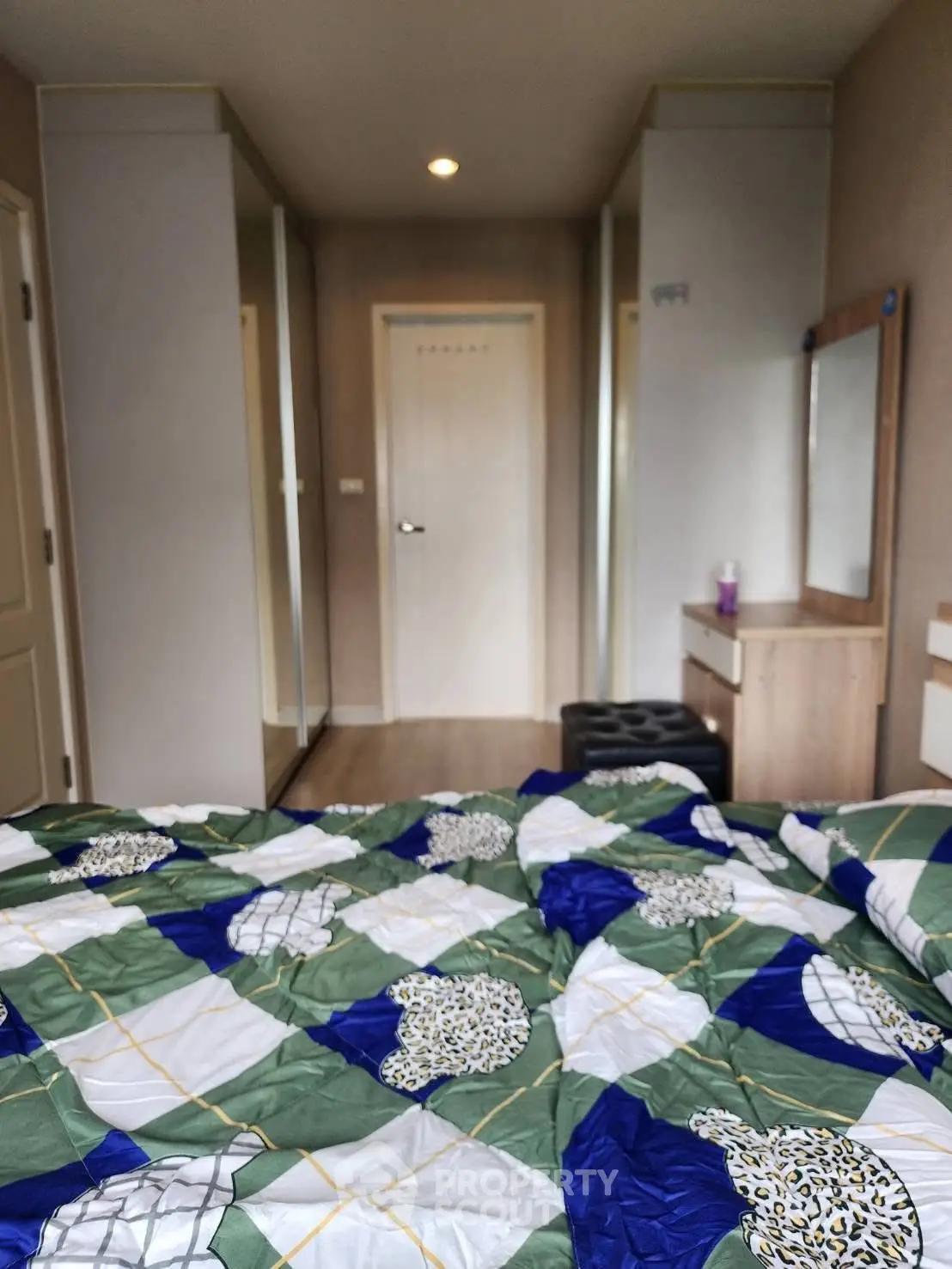 Cozy bedroom with mirrored closets and colorful bedding in modern apartment.
