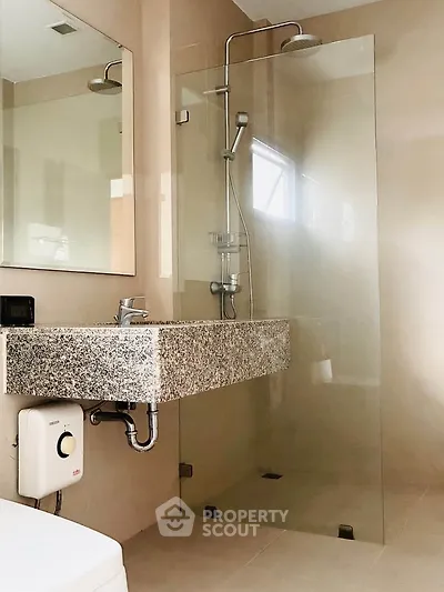 Modern bathroom with sleek glass shower and granite sink in contemporary home.
