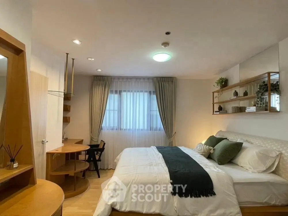 Cozy bedroom with modern decor and natural light, featuring a stylish workspace and elegant shelving.