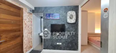 Modern apartment interior with stylish wall clock and TV, showcasing a cozy bedroom entrance.
