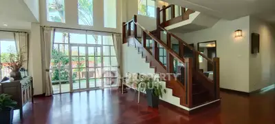 Elegant living room with wooden staircase and large windows offering garden view.
