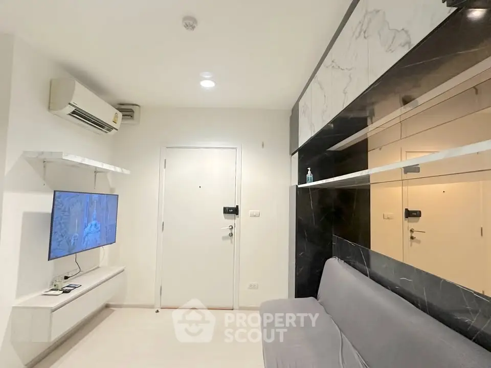 Modern living room with sleek design, featuring a wall-mounted TV, air conditioning, and stylish marble accents.