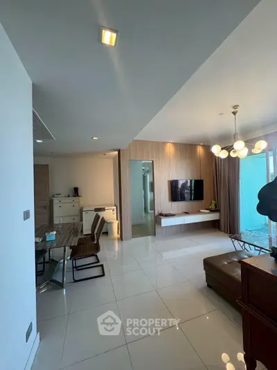 Modern living room with sleek design, featuring a wall-mounted TV, stylish lighting, and elegant furniture.