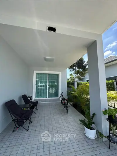 Charming covered patio with seating and greenery, perfect for relaxation.