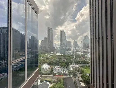 Stunning cityscape view from high-rise building window showcasing urban skyline and lush greenery.