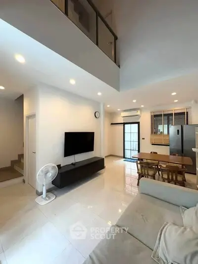 Modern open-plan living room with high ceiling and sleek furniture