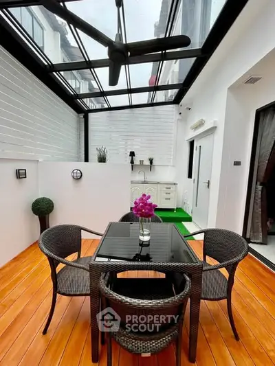 Stylish enclosed balcony with glass roof, modern furniture, and vibrant decor for a perfect urban retreat.