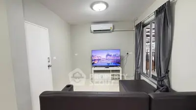 Modern living room with sleek furniture and large window, featuring a mounted TV and air conditioning.