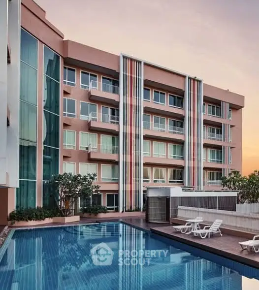 Modern apartment building with pool and stylish facade at sunset.