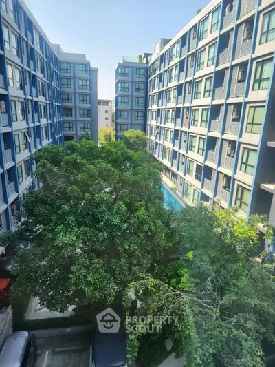 Modern apartment complex with lush greenery and pool view, ideal for urban living.