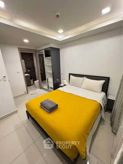 Modern bedroom with yellow bedding and sleek wardrobe in a stylish apartment.