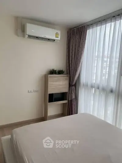 Cozy bedroom with air conditioning and large window with curtains