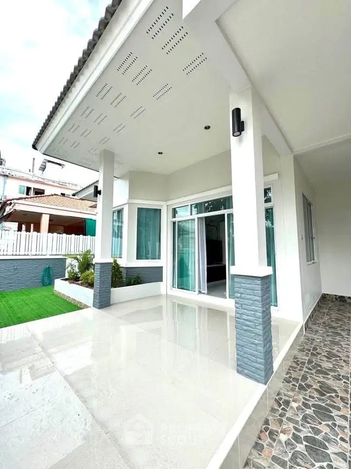 Modern white house exterior with spacious patio and large windows, perfect for family living.