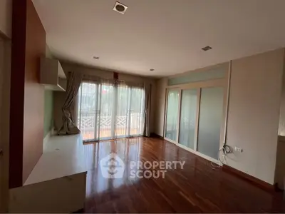 Spacious living room with hardwood floors and large windows for natural light