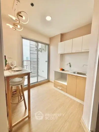 Modern kitchen with open layout and balcony access, featuring sleek cabinetry and stylish lighting.