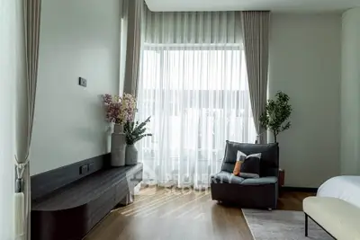 Elegant bedroom with large window, modern decor, and cozy seating area.