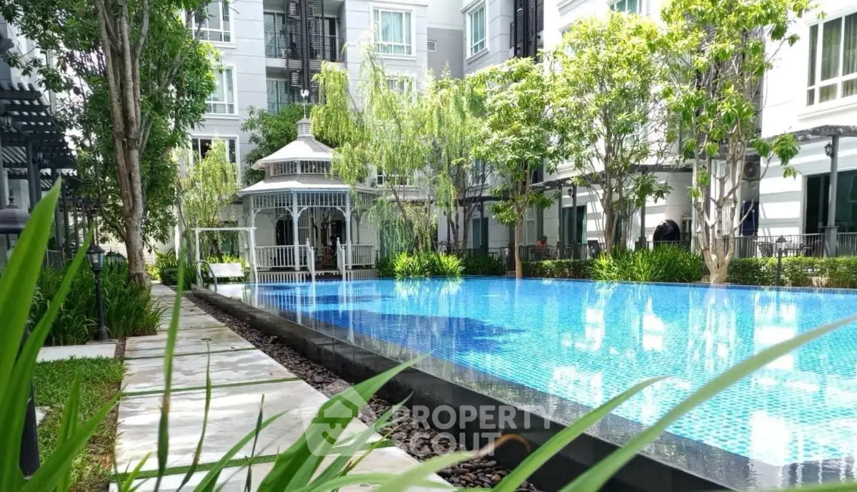 Luxurious condominium with serene pool and lush garden surroundings.