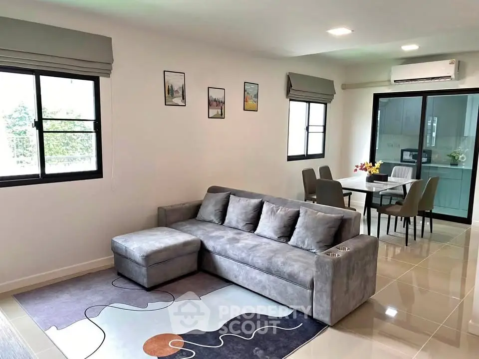 Modern living room with stylish gray sofa and dining area in open layout apartment.