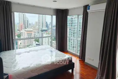 Spacious bedroom with stunning city view and large windows in modern apartment.