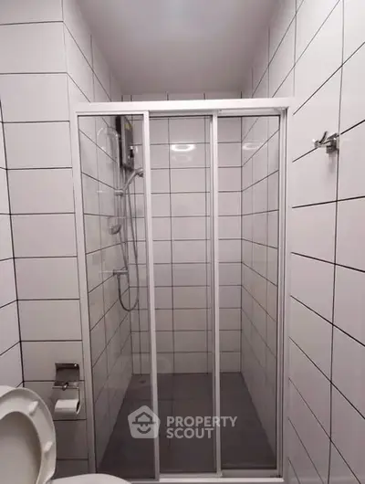 Modern bathroom with sleek shower enclosure and white tiled walls.