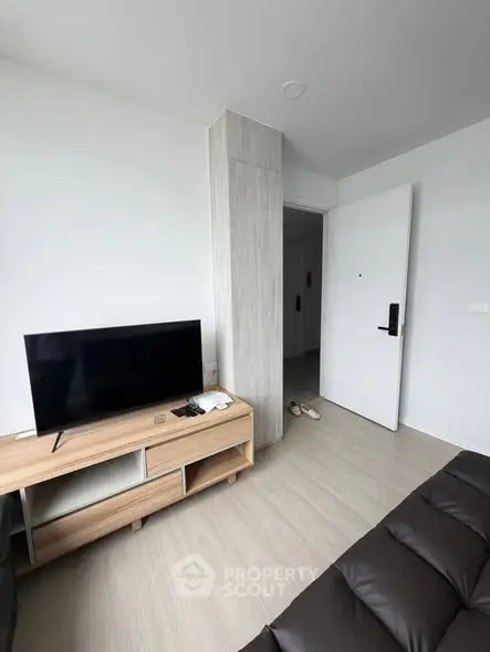 Modern living room with sleek TV stand and open door, showcasing minimalist design and bright ambiance.