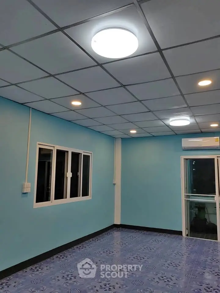 Spacious room with blue walls and tiled floor, featuring modern lighting and large windows.