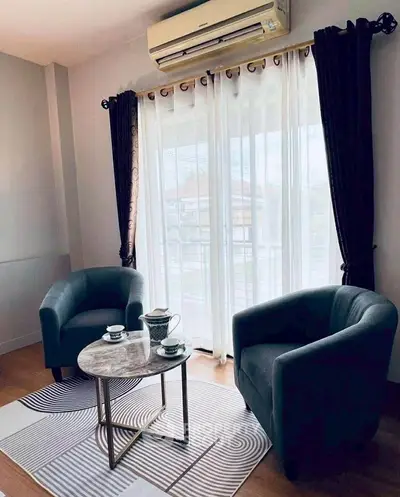 Cozy living room with elegant armchairs and a stylish coffee table by a sunlit window.
