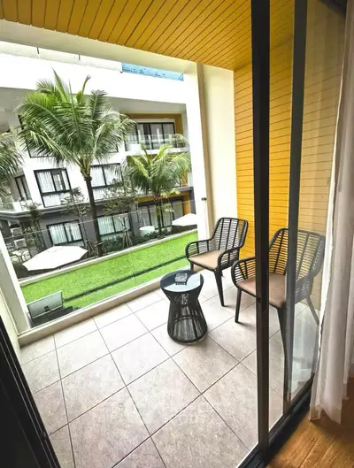 Charming balcony with cozy seating overlooking lush garden in modern apartment complex.