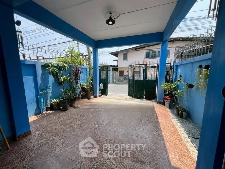 Charming blue-walled entrance with tiled flooring and lush potted plants, perfect for a welcoming home ambiance.