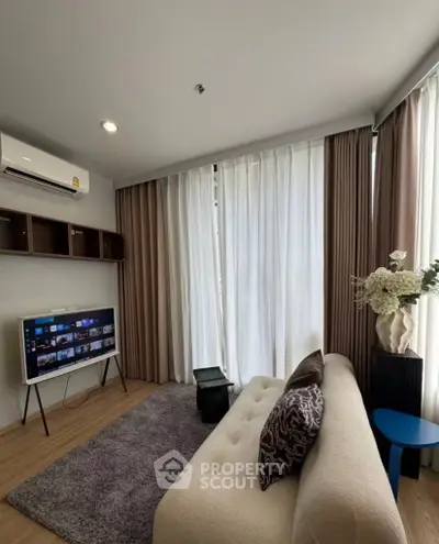 Modern living room with cozy sofa, stylish decor, and natural light from large windows.