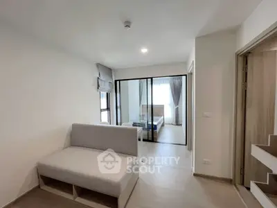 Modern apartment interior with cozy living area and bedroom separated by glass doors.