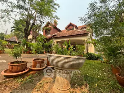 Charming estate with terracotta roof tiles nestled among lush greenery, featuring a serene garden and classical outdoor planters.