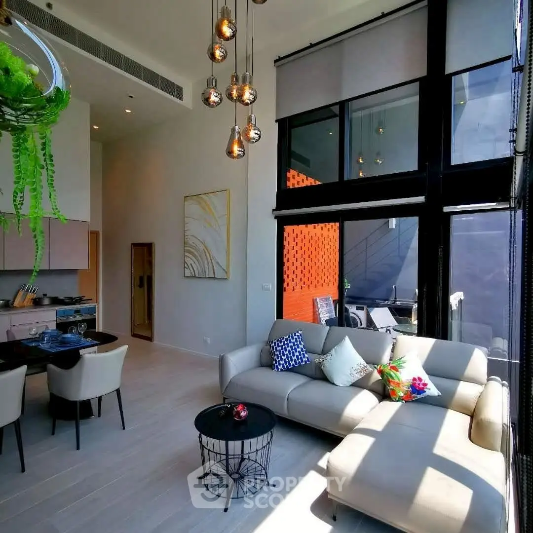 Modern living room with high ceilings and stylish decor, featuring a large sofa and dining area.