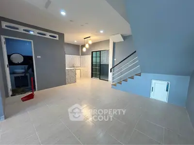 Spacious open-plan living area with modern kitchen and staircase, ideal for family gatherings.