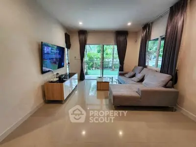 Spacious modern living room with large windows and garden view, featuring sleek furniture and elegant decor.