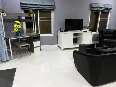 Modern living room with sleek black leather sofas and a stylish entertainment unit.