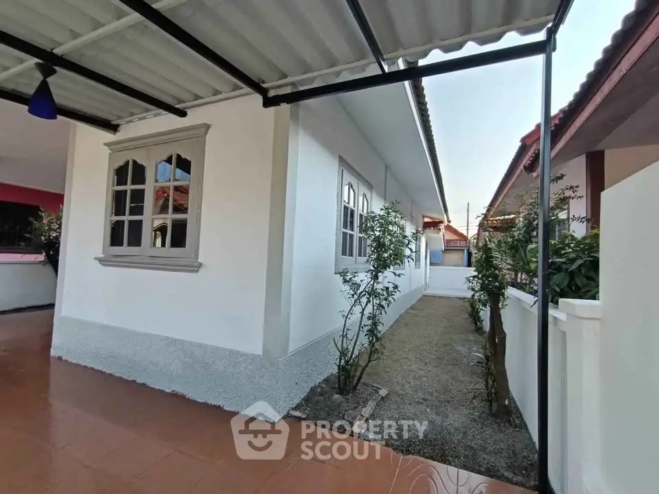 Charming single-story home with tiled patio and lush garden, perfect for serene living.
