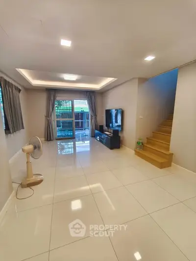 Spacious modern living room with sleek tile flooring and natural light, perfect for family gatherings.