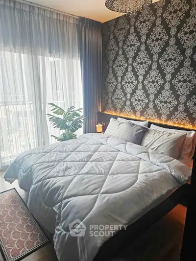 Luxurious bedroom with elegant wallpaper and large window offering natural light.