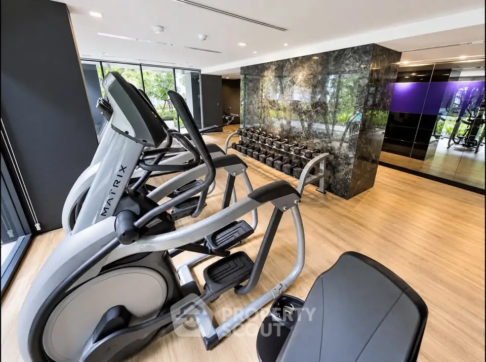 Modern gym with state-of-the-art equipment and sleek design in luxury residential building.