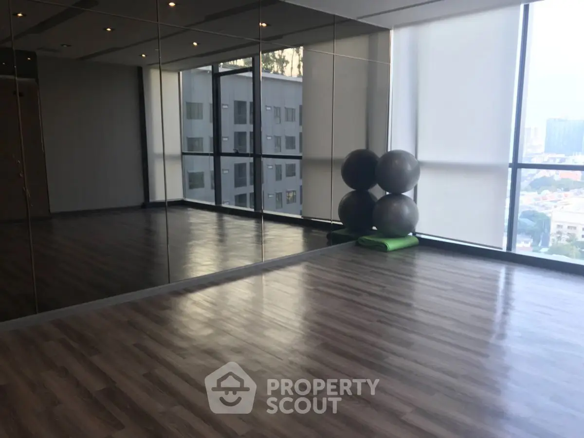 Spacious gym with mirrored walls and city view, perfect for fitness enthusiasts.