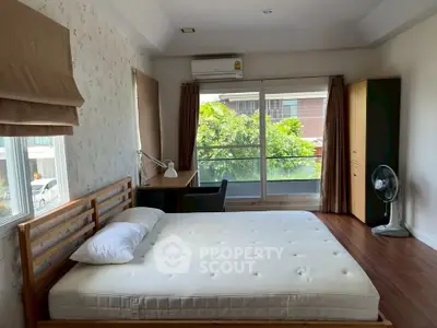 Spacious bedroom with large window and modern furnishings in a serene residential area.
